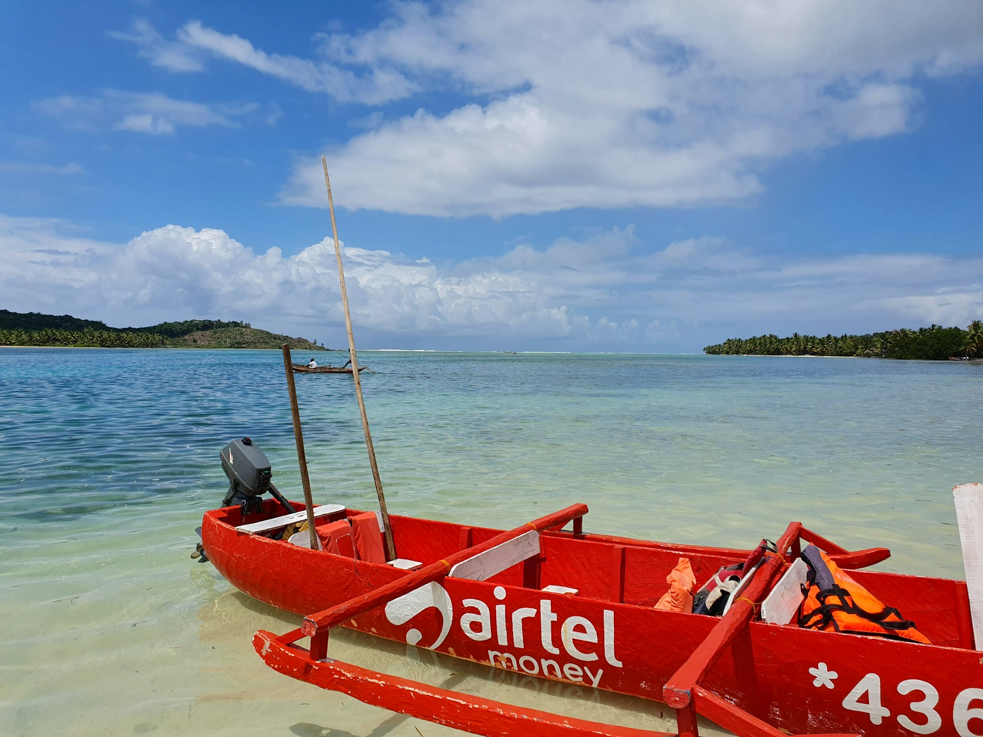 a red boat sitting on top of a sandy beach